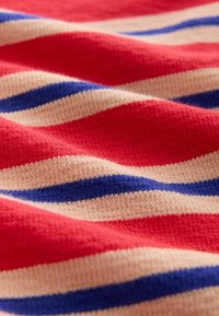 Tessuto a righe con colori rosso, crema e blu. La trama sembra morbida e lavorata a maglia con linee orizzontali ondulate.