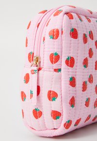 Sac pink matelassé avec un motif de fraises, fermeture éclair dorée et base arrondie. Tissu texturé avec des détails cousus.