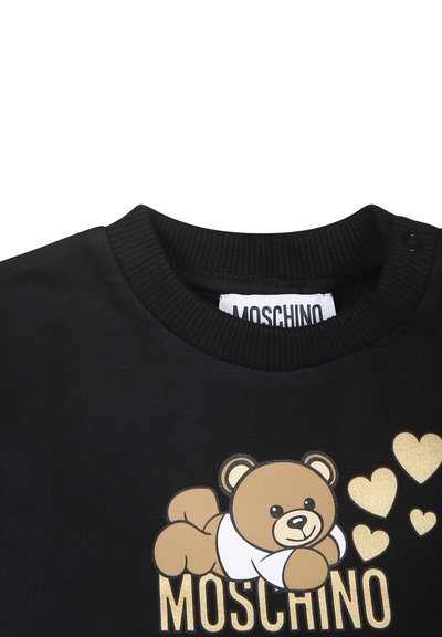 Sweatshirt noir avec un graphique d'ours brun sur une chemise blanche, des accents dorés et des cœurs, avec un col côtelé et une étiquette de logo.