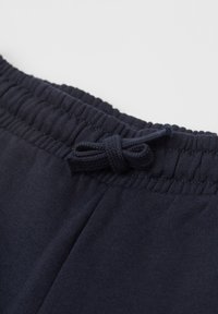 Granatowe bawełniane spodnie dresowe z szerokim elastycznym pasem w talii i ozdobną kokardą na środku, gładką fakturą i przeszyciami.