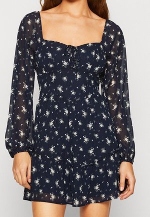 Marineblaues Blumen-Dress aus leichtem, durchscheinendem Stoff. Mit quadratischem Ausschnitt, langen Puffärmeln, Kordelzug und gerafftem Saum.