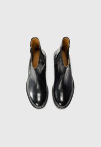 Botas de tornozelo em couro preto com laterais elásticas, bico redondo, textura suave e forro interior em tom bege. Design minimalista sem padrões.