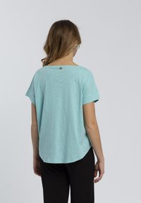 Top a maniche corte blu chiaro con scollatura rotonda, vestibilità rilassata e piccolo logo sul retro. Tessuto morbido e materiale leggero.