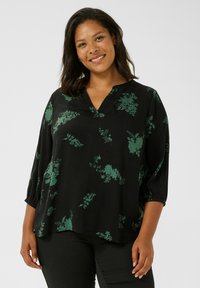 Schwarze Bluse mit grünem Blumenmuster, V-Ausschnitt und Dreiviertelärmeln, die an den Bündchen gerafft sind. Weicher Stoff mit lockerer Passform.