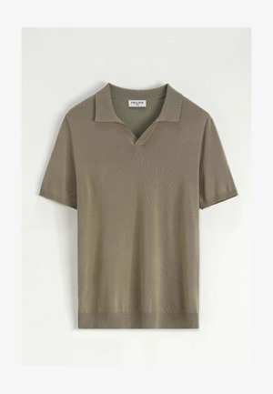 Polo à manches courtes en olive mute, fabriqué en tissu tricoté texturé, avec un col en V et un ourlet côtelé pour plus de structure.