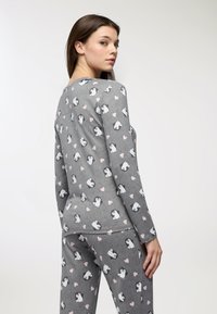 Set di pigiama grigio a maniche lunghe con motivo di pinguini e cuori rosa. Tessuto morbido e vestibilità comoda. Cuciture e polsini in evidenza.