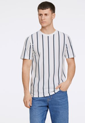 Stribet t-shirt i hvid med smalle marineblå lodrette striber. Korte ærmer, rund halsudskæring, lavet af let bomuldsstof. Blå jeans.