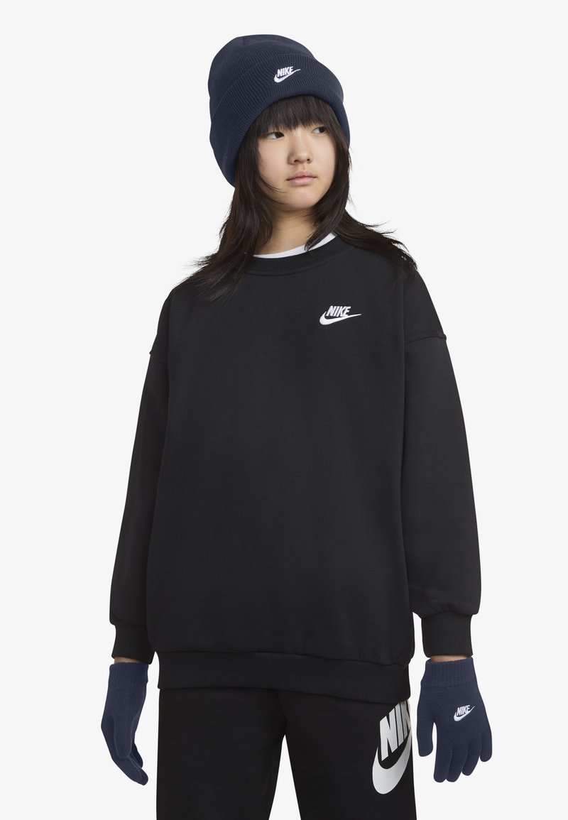Crna dukserica s bijelim Nike logom, uparena s tamnoplavim rukavicama i kapom. Glatka tkanina, širok kroj i kontrastni color akcenti.