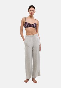 Bralette à carreaux en rouge, blanc et marine, avec des bretelles fines ; pantalon de survêtement gris à jambes larges, en tissu doux, avec une ceinture élastique.