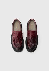 Bordeaux leren loafers met een gestructureerd krokodillenpatroon, franjes en een dikke zwarte zool. Merkennaam zichtbaar op de binnenzolen.