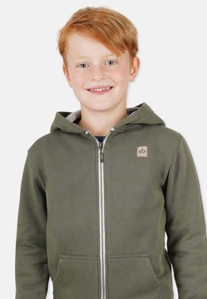 Grüne Zip-Hoodie aus weichem Material, mit einer Fronttasche und einem Etikett auf der Brust, sowie einem grauen Innenfutter in der Kapuze.