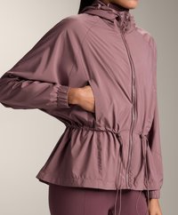 Veste légère rose avec taille cintrée, capuche et fermeture éclair. Comprend des poignets élastiques et des poches latérales pour une fonctionnalité supplémentaire.