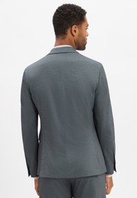 Grijze textuur blazer met een getailleerde snit, notched revers en achterste ventilatie, weergegeven vanuit de achteraanzicht.