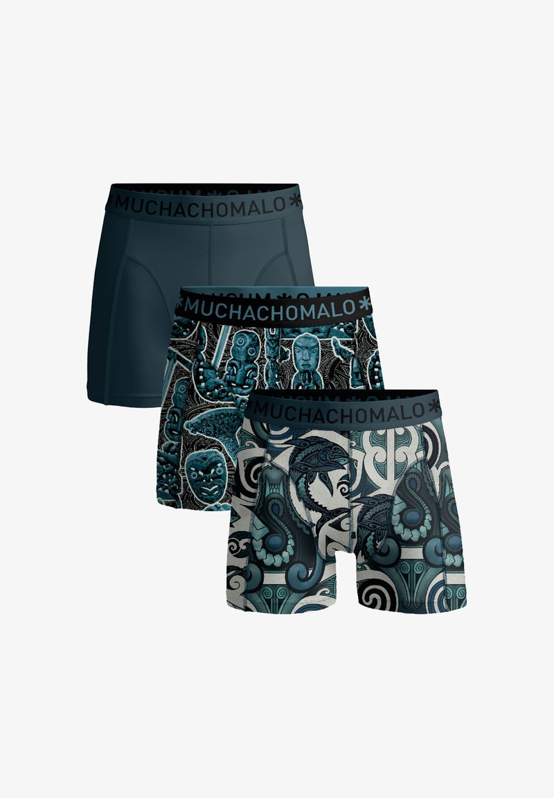 Trois boxers pour hommes avec ceintures élastiques marquées "Muchachomalo" ; un uni bleu foncé, deux avec des motifs tribaux bleus et noirs.