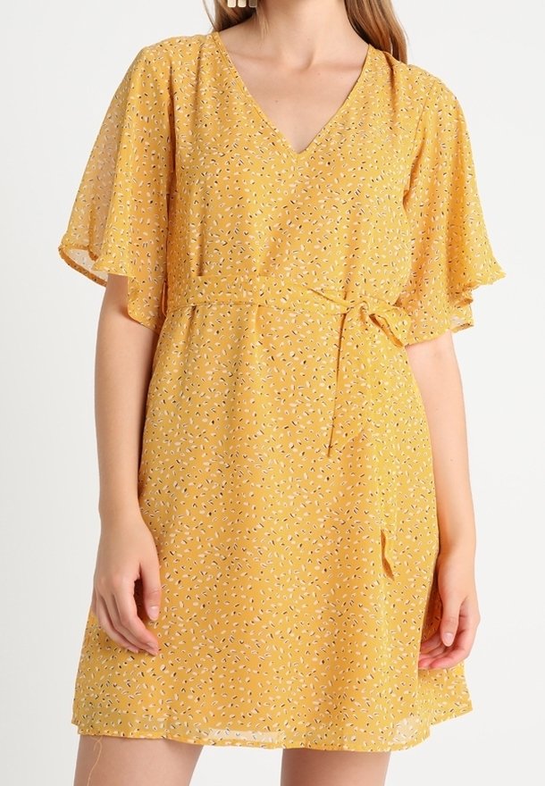 Robe florale jaune avec un décolleté en V, des manches courtes à volants et un lien à la taille. Fabriquée en tissu léger avec une texture douce.