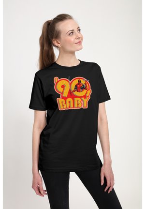 T-shirt en coton noir présentant un graphique coloré d'un personnage brandissant des armes, avec un texte en gras jaune et rouge disant "90 BABY."