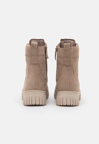 Bottines en cuir beige avec finition texturée, fermetures éclair sur les côtés, bout arrondi et semelles en caoutchouc striées présentant des rainures de couleur claire.