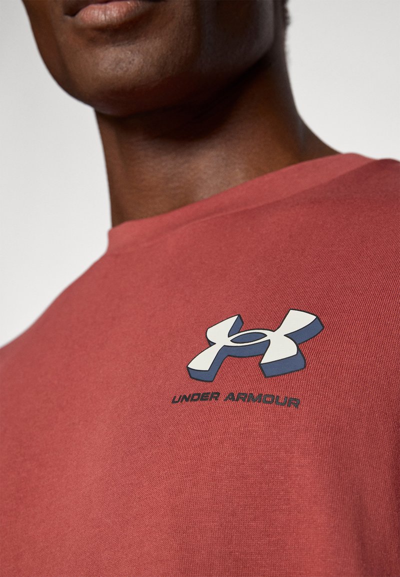 Camiseta de algodón roja con mangas cortas, que presenta un logotipo 3D en azul y blanco en el pecho y una textura suave.