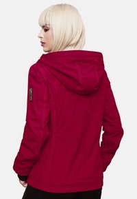 Rød vandtæt jakke med hætte, featuring en lynlåslukning foran, elastiske manchetter og et logo-patch på venstre ærme. Glat stofstruktur.