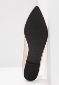 Talons aigus avec une tige rose métallisée et une semelle en caoutchouc. Présente une adhérence texturée sur la semelle. Taille 5, marquée "Fabriqué en Chine."