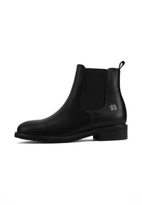 Stivale Chelsea nero realizzato in pelle liscia con pannelli elastici laterali, punta rotonda e tacco basso a blocco. Presenta un accento metallico con marchio.