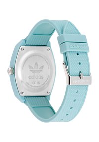 Montre numérique avec un boîtier carré en acier inoxydable argenté, un bracelet en silicone bleu clair, des accents texturés et un matériel de marque.