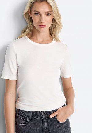 White short-sleeve t-shirt with a round neckline, made of smooth fabric, paired with high-waisted black jeans, featuring side pockets.