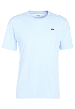 Hele sinine lühikese varrukaga t-särk, mis on valmistatud puuvillast, millel on vasakul rinna küljes väike must ja punane Lacoste logo.