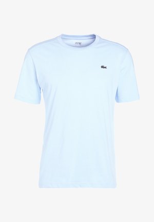 Hele sinine lühikese varrukaga t-särk, mis on valmistatud puuvillast, millel on vasakul rinna küljes väike must ja punane Lacoste logo.