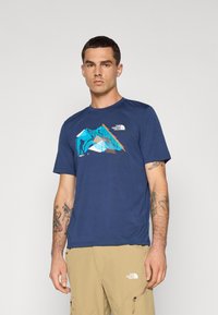 Donkerblauwe T-shirt met korte mouwen van stof, versierd met een kleurrieke bergafbeelding en een logo op de borst. Soepele textuur, casual pasvorm.