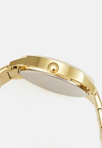 Gold-tone wristwatch with a polished metal case, textured crown, and a smooth round face. Band features interlocking links for secure fit.