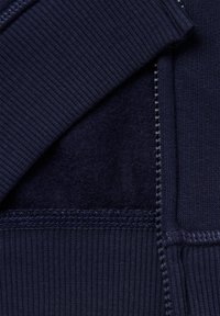Felpa blu navy con tessuto a costine, che mostra un morbido rivestimento interno, cuciture a contrasto e chiusura con zip.