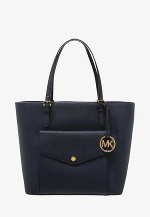 Bolso tote de cuero azul marino con bolsillo frontal de solapa, asas dobles y un colgante con el logo de Michael Kors en tono dorado colgando de una de las asas.