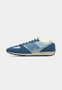 Blue and light blue suede and mesh sneaker with cream laces, featuring a large "N" logo, a textured sole, and a low-profile design.