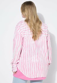 Langarmhemd mit pink-weißen, gewellten Streifen, aus weichem Stoff, lockerem Schnitt, abgerundetem Saum und Knopfmanschetten.