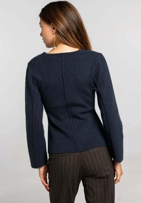 Suéter de punto azul marino con cintura ajustada y mangas largas, que presenta un patrón texturizado y una costura recta en la parte trasera.