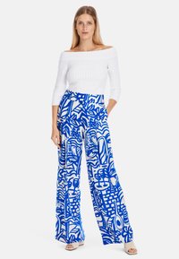 Blue and white patterned wide-leg pants with a high waist, paired with a fitted, off-the-shoulder white ribbed top. Smooth, lightweight fabric.