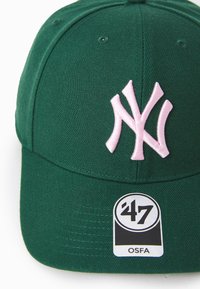 Grønn cap laget av stoff, med en rosa brodert NY-logo. Inkluderer et svart og hvitt etikett som viser "47" og "OSFA."