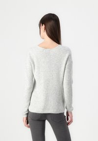 Light grey knit sweater with a loose fit, ribbed texture, and a wide neckline. Features long sleeves and a slightly frayed hem.