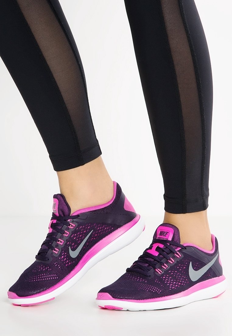 Scarpe da ginnastica viola e rosa con tomaia in mesh, accenti grigi e suola bianca, abbinate a leggins neri con pannelli laterali trasparenti.