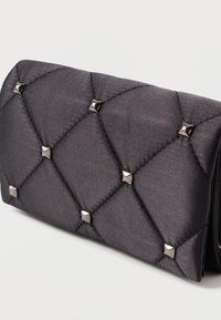 Μαύρο σατέν πορτοφόλι με ραφές σε σχέδιο διαμαντιού, διακοσμημένο με μεταλλικά καρφάκια και λεία υφή. Συμπαγές ορθογώνιο σχήμα.