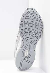 Grå atletisk skosula med texturerad gummi, som har en formad design och flexgropar för grepp och rörelse.