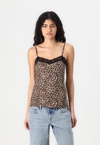 Cami-top i leopardmönster, med svarta spetsdetaljer, justerbara axelband och en mjuk tygtextur. Kombinerad med hög midja ljusa jeans.