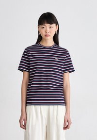 T-shirt rayé bleu marine avec des accents rouges et bleu clair, col rond, manches courtes, comportant un petit logo vert sur la poitrine.