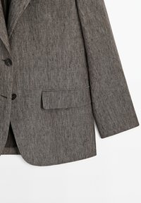 Blazer marrone con texture, due bottoni neri, tasca a patta sul davanti e maniche lunghe su uno sfondo bianco.
