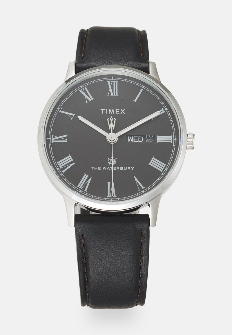 Relógio com pulseira de couro preto, caixa redonda prateada, mostrador cinza, números romanos brancos e data para quarta-feira.