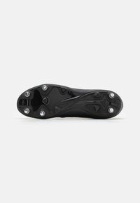 Suela de zapatilla de fútbol negra con una base con tacos; presenta una superficie lisa y texturizada y seis tacos metálicos desmontables para una mejor tracción.