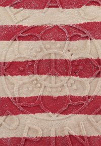 Tissu rayé rouge et beige avec un éclat métallique ; présente un logo de couronne en relief et du texte. Texture douce avec des motifs en relief visibles.