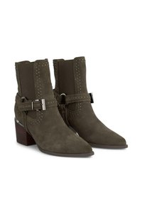 Zamszowe botki do kostki w oliwkowym kolorze z ostro zakończonym noskiem, bocznymi elastycznymi panelami, detalami w postaci srebrnych ćwieków oraz dekoracyjnym paskiem z klamrą.