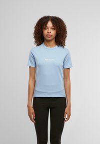 Világoskék pamut póló, kerek nyakkivágással, rövid ujjakkal, elöl fehér "Juicy Couture Sport" logóval. Simább textúrájú.